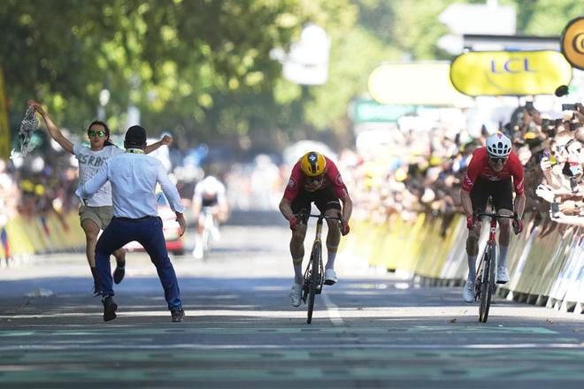 Nór Jonas Abrahamsen (uprostred) a Švajčiar Mauro Schmid v záverečnom špurte vedľa protestujúceho počas 11. etapy cyklistických pretekov Tour de France z Toulouse do Toulouse (156,8 km).
