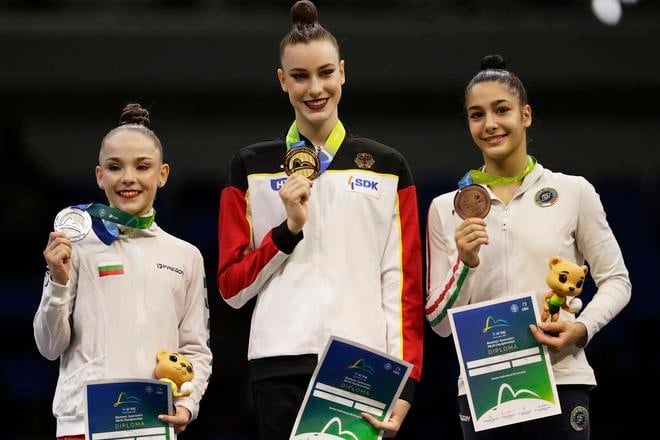 Nemecká reprezentantka v modernej gymnastike Darja Varfolomejevová (uprostred) pózuje na pódiu so zlatou medailou po triumfe vo finále viacboja jednotlivkýň na majstrovstvách sveta v brazílskom Riu de Janeiro v piatok 22. augusta 2025. Druhá skončila Bulharka Stiliana Nikolovová (vľavo) a bronz získala päťnásobná majsterka sveta Sofia Raffaeliová z Talianska.