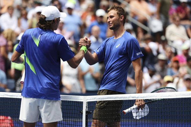 Austrálsky tenista Alex de Minaur.(vľavo) si podáva ruku s porazeným Švajčiarom Leandrom Riedim po jeho výhre v osemfinále dvojhry mužov na grandslamovom turnaji US Open v New Yorku.