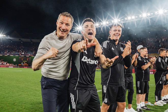 Diarmuid O'Carroll v objatí svojho šéfa Briana Priskeho, pre ktorého riadi útok Sparty.