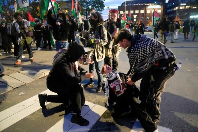 Pro-palestínski demonštranti pomáhajú demonštrantke po policajnom zásahu odstrašujúcim prostriedkom pred štadiónom Ullevaal počas zápasu I-skupiny Nórsko - Izrael európskej kvalifikácie na MS 2026 v Osle 11. októbra 2025.