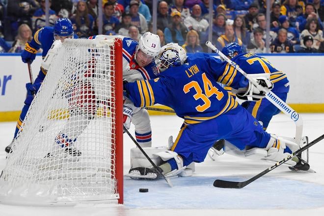 Útočník New York Rangers Alexis Lafreniere (vľavo) strieľa gól do siete brankára Buffalo Sabres Alexa Lyona.