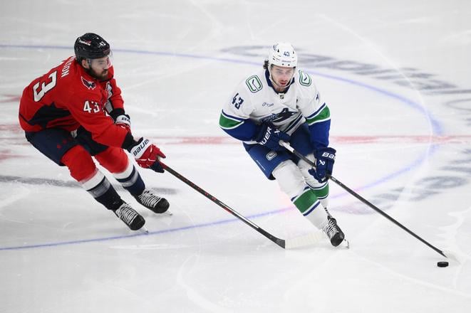 Obranca Vancouveru Canucks Quinn Hughes v súboji o puk s krídelníkom Washingtonu Capitals Tomom Wilsonom.