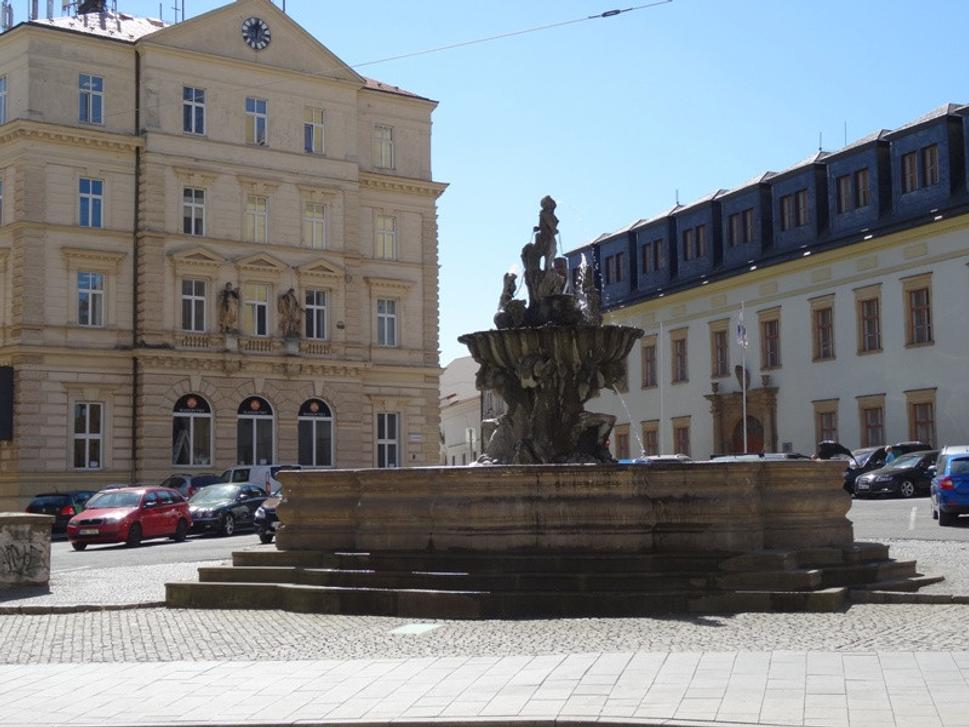 Fontána Tritónov. Tritóni v pokľaku držia na svojich ramenách mušľu, v ktorej sa nachádza chlapec a dva okrídlené psy.
