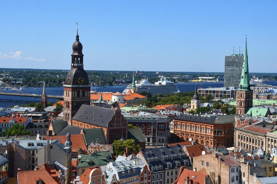 Veža vpravo patrí Katedrále sv. Jakuba, vľavo vidíme majestátny Rižský dóm. Kúsok za ním už tečie rieka Daugava. Veľká loď s turistami priplávala zo Štokholmu. V pravidelných intervaloch Riga udržuje lodné spojenie aj s Helsinkami.