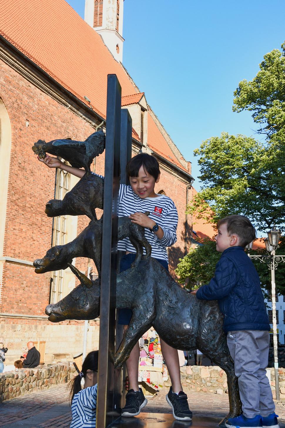 Zobák kohúta prinášajúceho najväčšie šťastie je tak vysoko, že k nemu zo zeme nikto nedosiahne. Šikovní chlapci si pomohli, vyliezli na podstavec. Nám starším musí postačiť ňufák psa.