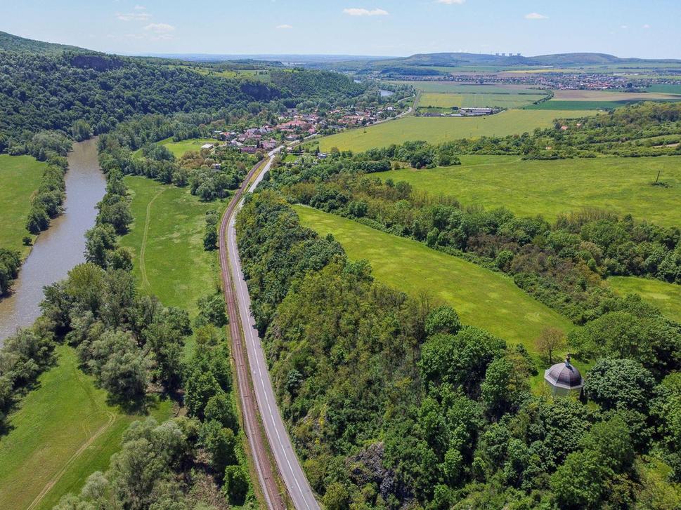 Pohľad na hradisko od severu. Na obrázku je to zelená trávnatá plocha, tiahnúca sa od kaplnky na juh, v smere toku rieky. Do údolí k rieke pod bralom, na ktorom stojí kaplnka, bolo treba vtesnať cestu a železnicu.