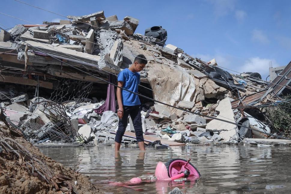 Palestínsky chlapec stojí po členky vo vode na mieste jeho niekdajšieho domu v Gaze, z ktorého ostali len trosky.