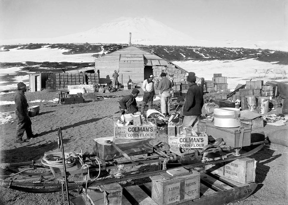 Vylodenie a stavba chaty na Cape Evans, v pozadí sopka Mount Erebus