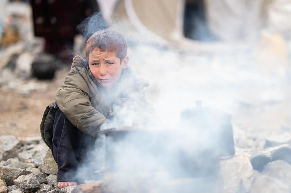 Ezatullah, 10, sa snaží zohriať pri ohníku v tuhej afganskej zime.
