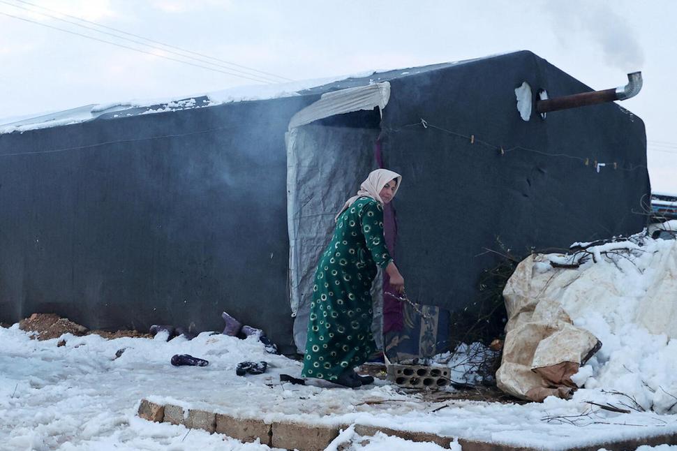 Január 2022: Žena sa zohrieva pri skromnom ohníku v tábore pre vnútorne vysídlené osoby blízko mesta Afrin v provincii Aleppo kontrolovanej vzbúrencami