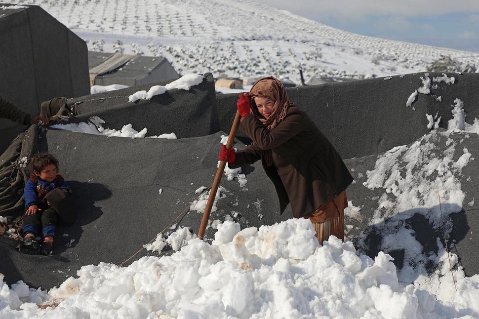 Január 2022: Žena odhŕňa sneh zo strechy stanu v tábore pre vnútorne vysídlené osoby v meste Raju v provincii Aleppo kontrolovanej vzbúrencami