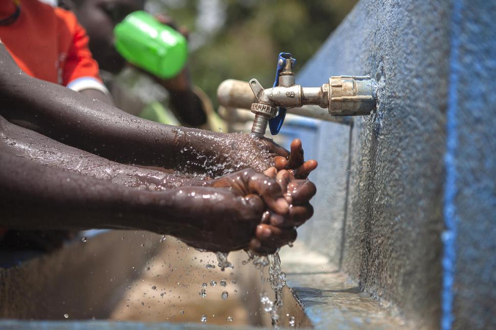 Uganda, 2022: Nakwang Prisca, 15, žiačka miestnej základnej školy v oblasti Karenga si umýva ruky pred škoským obedom. UNICEF tejto škole poskytol spoľahlivý zdroj pitnej vody, ktorý slúži na mnohé účely - poskytuje vodu na pitie, varenie, zalievanie malých políčok či čistenie a upratovanie školy.