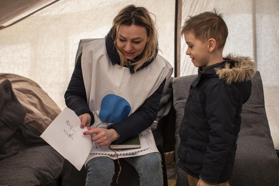 Detská psychologička pracujúca pre miestnu neziskovú organizáciu sa rozpráva s Igorom v stane Modrý bod v Moldavsku