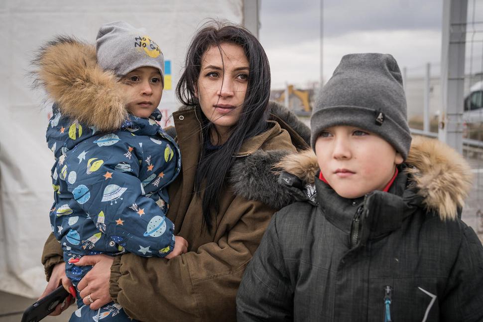 Olga stojí pred stanom s jej dvomi deťmi Timorom a Vladimírom