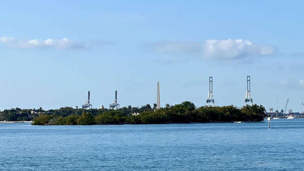 Ten obelisk vyzerá v porovnaní so žeriavmi prístavného ostrova Dodge Island, ktorý je až ďaleko vzadu maličký.