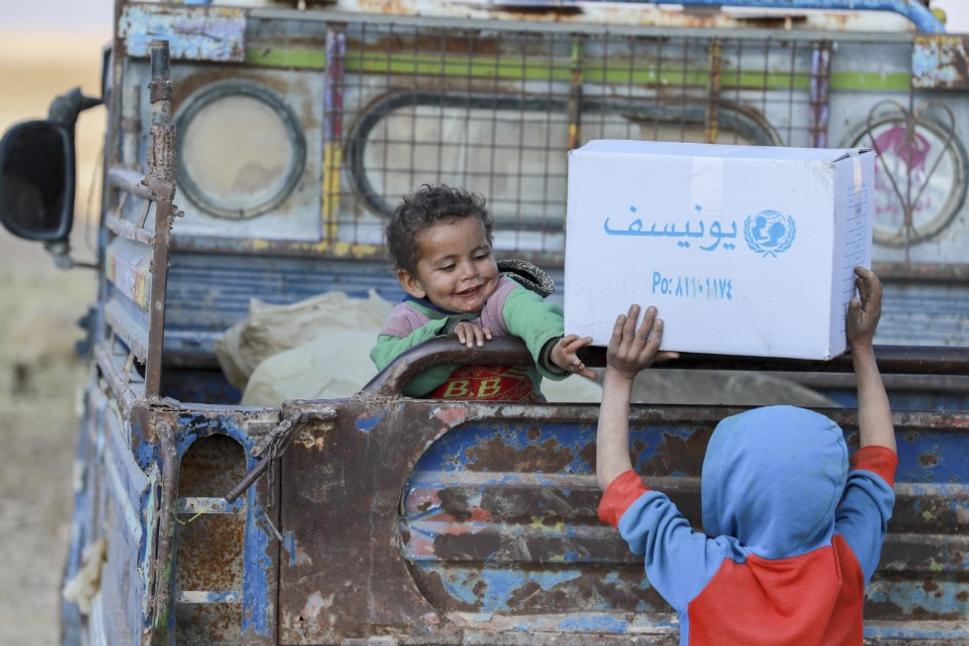 Vnútorne vysídlené deti pomáhajú svojim rodičom počas distribúcie zimného oblečenia v tábore Kabbish Wasti, Raqqa, Sýria.