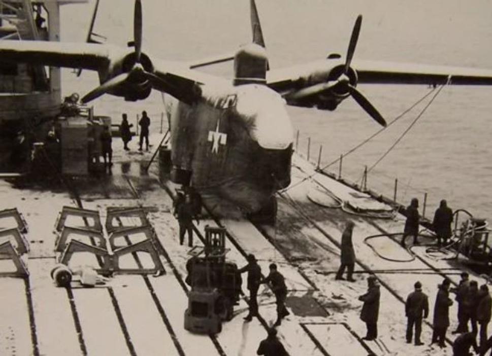Posádka lode, napriek nepriaznivému počasiu, pripravuje lietajúci čln PBM-5 Mariner na let.