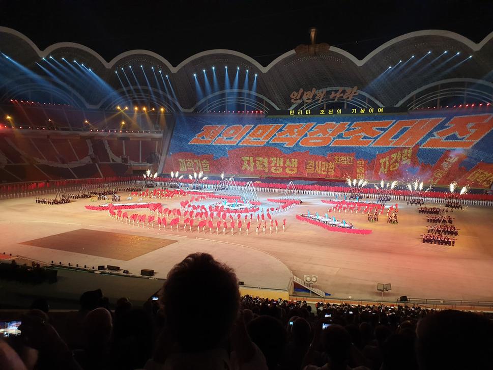 Tribúna oproti bolo asi 30 000 interprétov, ktorí synchronizovane menili obrázky tak, že tvorili akoby monitor.