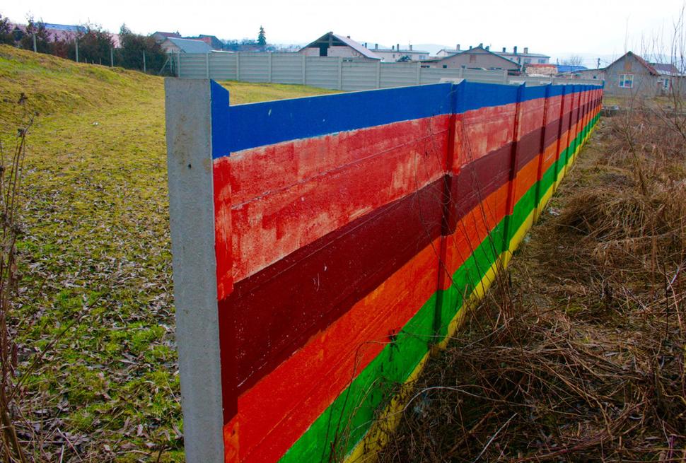 Múr v Ostrovanoch oddeľuje miestnu rómsku osadu (vpravo od múru) a záhrady ďalších obyvateľov obce (vľavo, hore svahom). Február 2016.