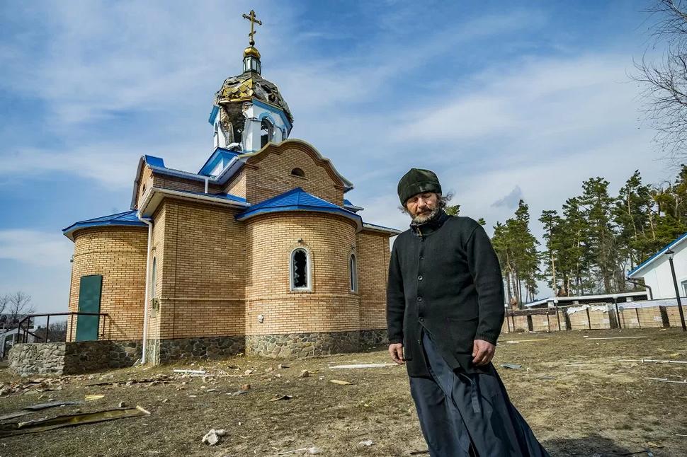 Kňaz Romanov z Jasnohorodky stojí pred svojím kostolom po tom, čo ho zasiahlo ostreľovanie