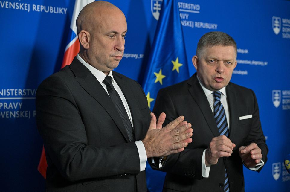 Minister dopravy a premiér. Medliaci si ruky a stojaci pred symbolmi svojich dojných kráv.