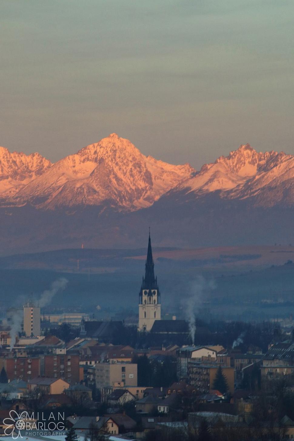 Pohľad na dominantnú novoveskú vežu v pozadí s Vysokými Tatrami.