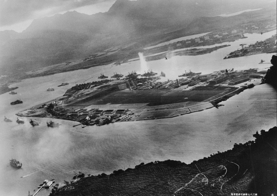 Začiatok útoku na americké bojové lode v Pearl Harbor. Fotografia z lietadla neznámeho japonského letca. Zdroj: https://en.wikipedia.org/wiki/Attack_on_Pearl_Harbor#/media/File:Attack_on_Pearl_Harbor_Japanese_planes_view.jpg. Licencia Public domain.