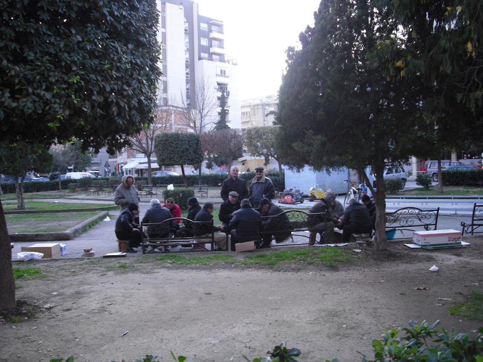 Páni hrajúci domino, karty a šach v centre mesta.