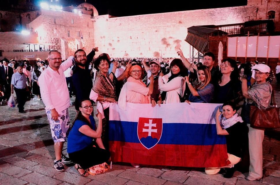 Členovia skupiny ukazujú na Múr nárekov v pozadí.