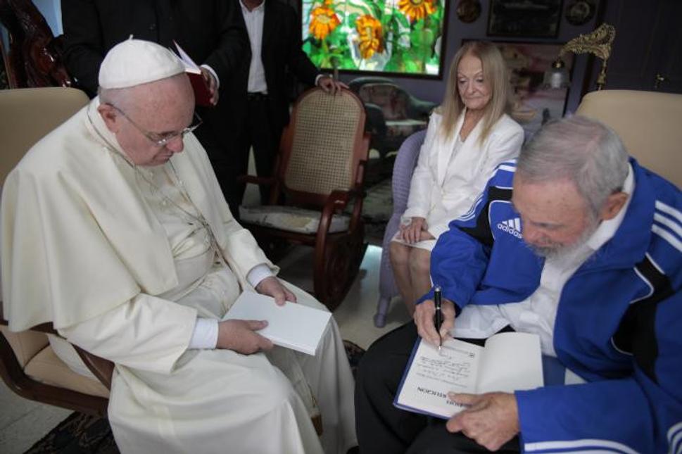 Fidel píše venovanie pre Františka na svoju knihu Fidel y la religión (Fidel a náboženstvo), v pozadí Fidelova manželka Dalia Soto del Valle